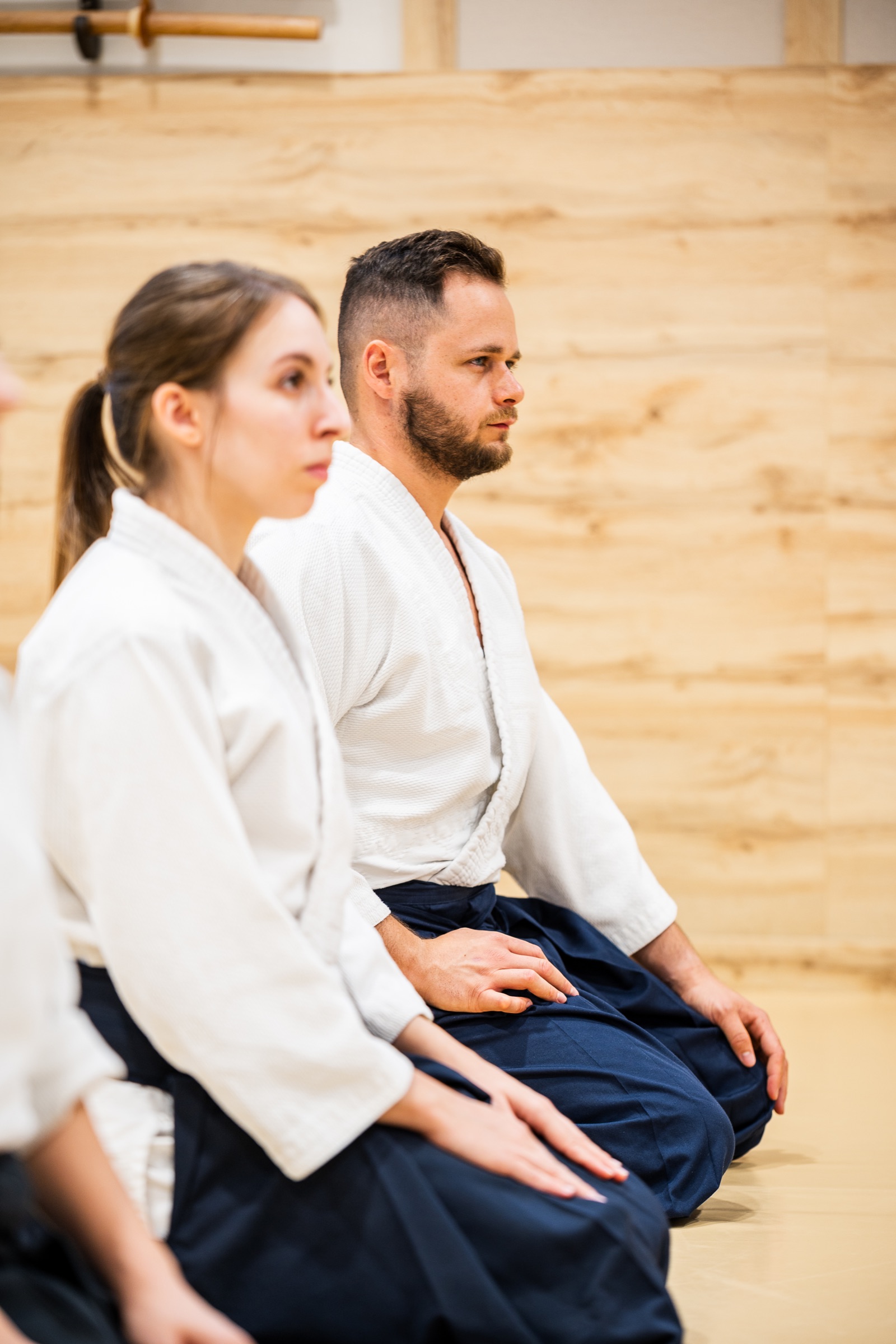 Two aikidoka in seiza, following the explanation.